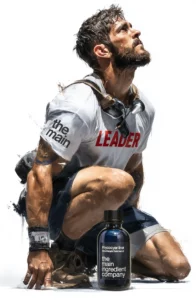 Athlète 'Leader' musclé (CrossFit, Hyrox, Musculation) agenouillé, concentré, avec flacon de Phycocyanine ω The Main Ingredient Company (TMIC) pour performance, force et récupération.